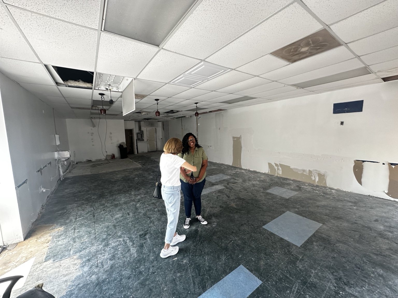 Two people standing inside the unfinished DOXA District space, with bare walls and flooring under construction.