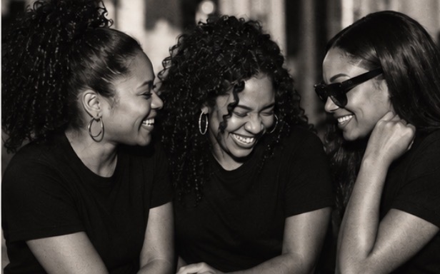 Three women laughing together around a dinner table.